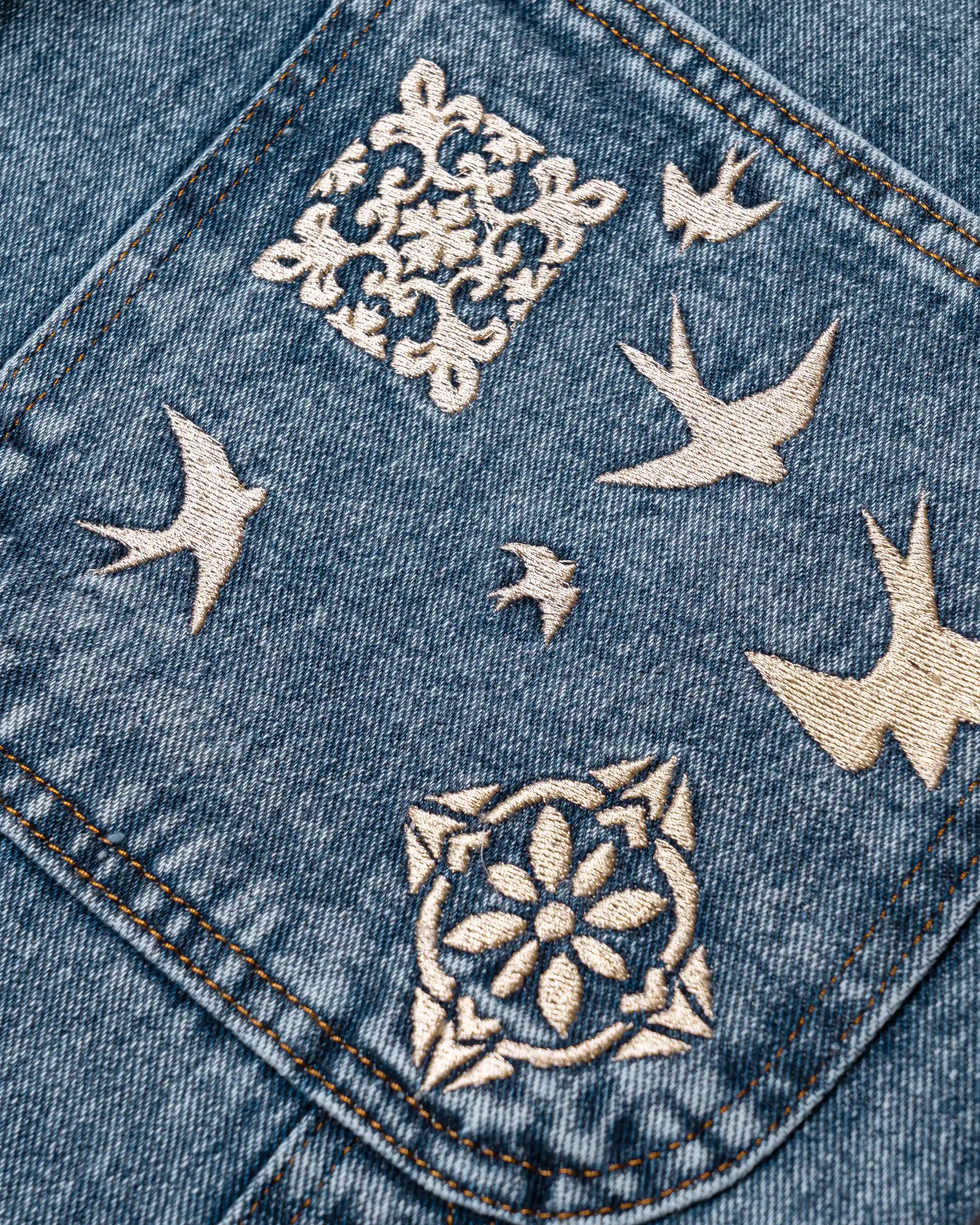 100% Cotton denim
Blue fade out wash
Embroidered Lisbon's tiles and swallows on back pocket and front leg
2 angled front pockets with classic coin pocket
2 back patch pockets featuring decorative embroidery
2 side utility pockets with reinforced panel construction
Relaxed, knee-length fit with wide leg opening
Branded EMENTA patch on rear waistband
Made in Portugal