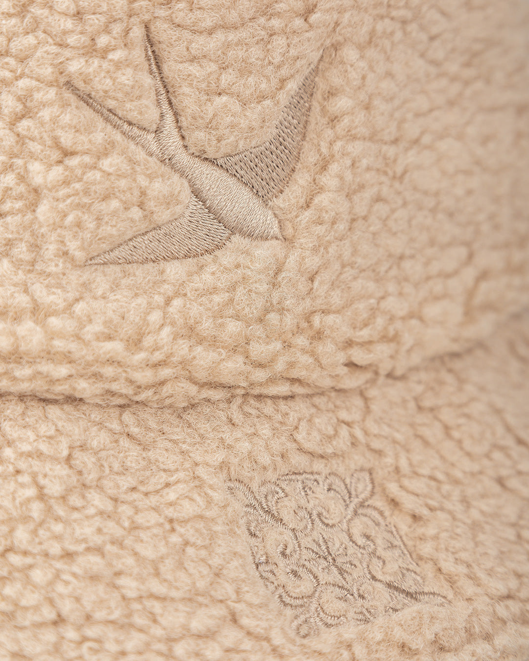 A classic bucket hat crafted entirely from soft sherpa, offering warmth and texture in an off-white color. It features the intricate Lisa design, inspired by Lisbon’s rich culture, incorporating traditional tiles and swallows for a unique touch. Designed for both style and comfort, this hat is a statement piece for any season.